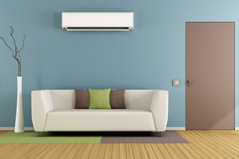 Why Ductless Is the Way to Go. Contemporary living room with white sofa, air conditioner and closed door.