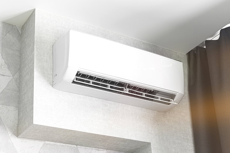 White mini-split air conditioning unit mounted high on a wall.