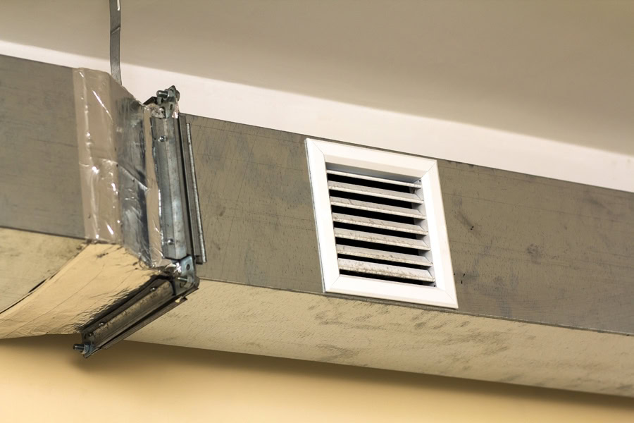 Ventilation pipes in silver insulation material hanging from the ceiling inside new building.|ductwork