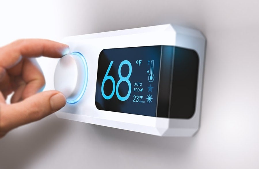 Homeowner's Hand Adjusting the Temperature on a Thermostat|Homeowner's Hand Adjusting the Temperature on a Thermostat