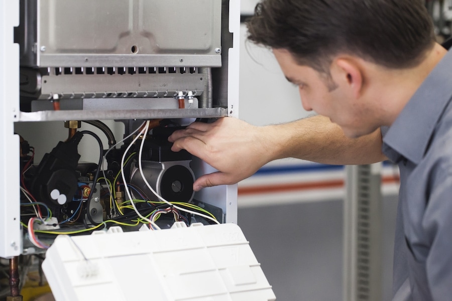 Technician servicing furnace. 5 Reasons to Schedule a Fall Furnace Clean and Check.