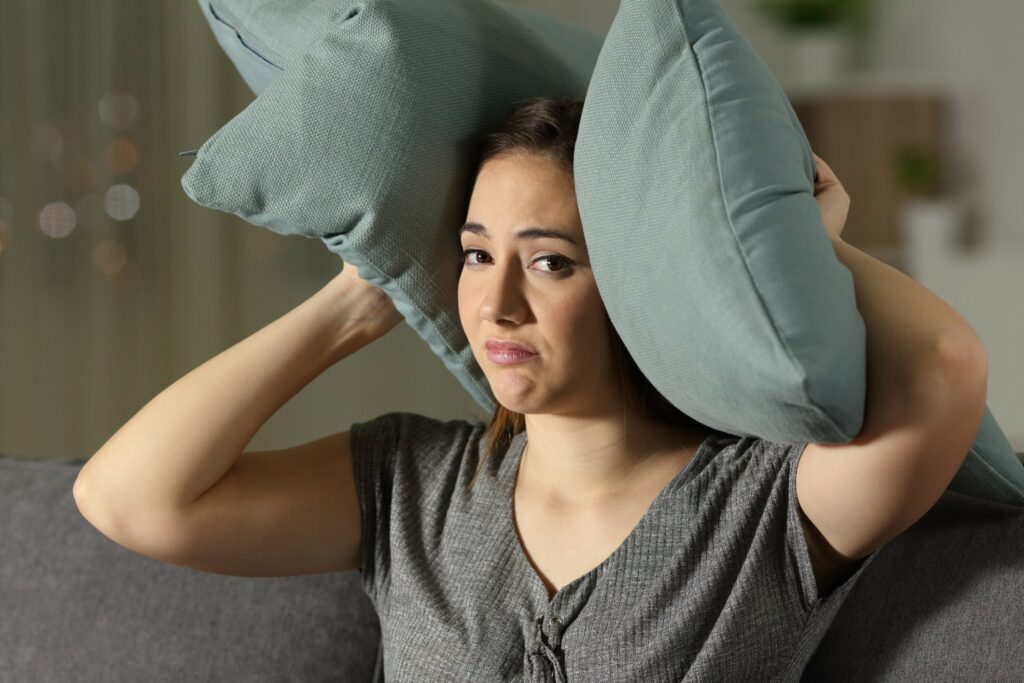 Woman covering ears due to loud air conditioner in home|